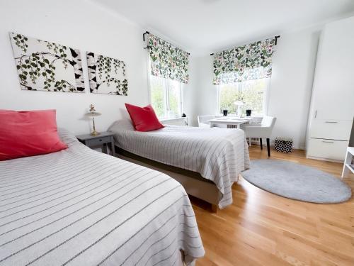 2 Betten in einem Zimmer mit weißen Wänden und roten Kissen in der Unterkunft Strandgården Karlstad in Karlstad