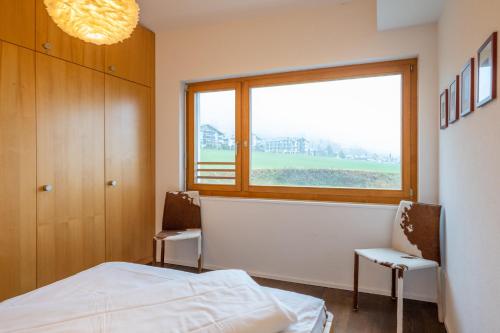 a bedroom with a bed and a large window at Edelweiss Ferienwohnung, Panoramablick in Flims