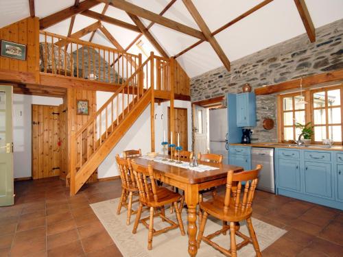 a kitchen with a wooden table and wooden stairs at Yr Hen Gof in Mathry