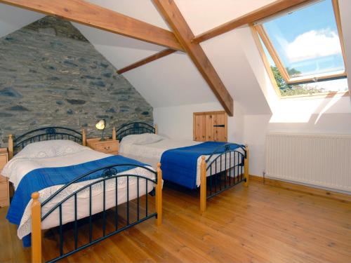 two beds in a attic bedroom with a stone wall at Yr Hen Gof in Mathry