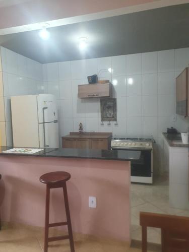 a kitchen with a counter and a refrigerator and a stool at Casa temporada da Nenê in Ipitangas