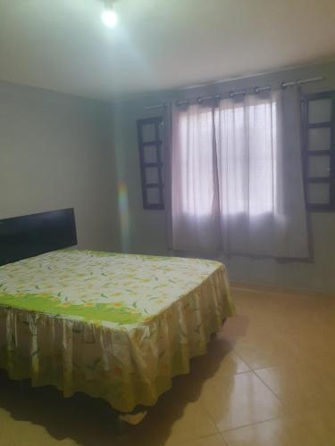 a bedroom with a bed in a room with a window at Casa temporada da Nenê in Ipitangas