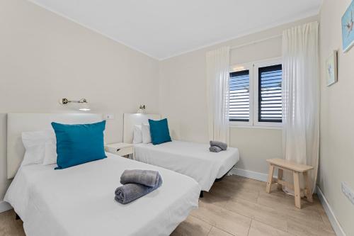 - 2 lits dans une chambre blanche avec des oreillers bleus dans l'établissement Home2Book Modern Apt Puerto del Carmen, Terrace, à Puerto del Carmen