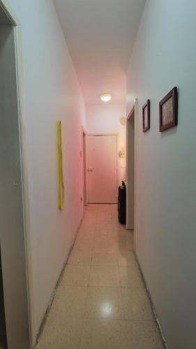 un pasillo con una puerta rosa y una pared blanca en Your room, en St Paul's Bay