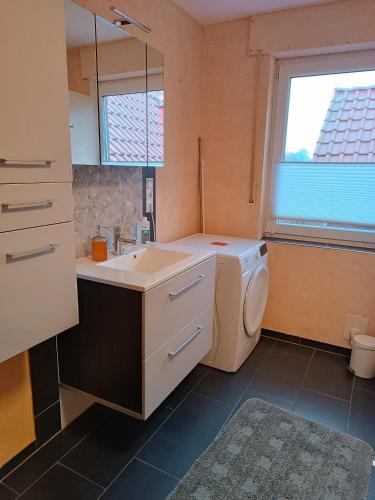 a bathroom with a sink and a washing machine at Gästehaus Atrico Schleuse Wg 1 in Surwold