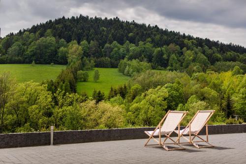 2 chaises assises sur une terrasse donnant sur un champ dans l'établissement Honey Inn, à Kamianna