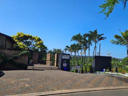 a gate with palm trees in front of a fence at Hillton Manor Guest House in Richards Bay