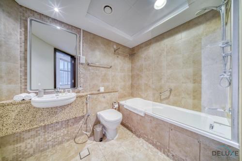 a bathroom with a tub and a sink and a toilet at Spacious Studio at Sky Gardens DIFC by Deluxe Holiday Homes in Dubai