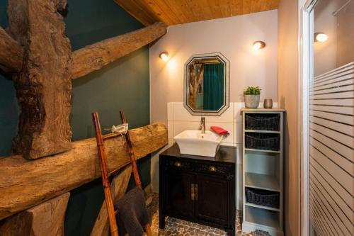 ein Badezimmer mit einem Waschbecken und einem großen Baum aus Holz in der Unterkunft Gîte l'Envol in Saint-Pierre-de-Clairac