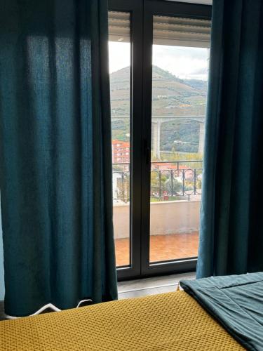 a bedroom with blue curtains and a window with a view at CasaMaeDouro in Peso da Régua