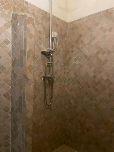 y baño con ducha y paredes de azulejos marrones. en Riad Gasämbre Touareg, en Marrakech