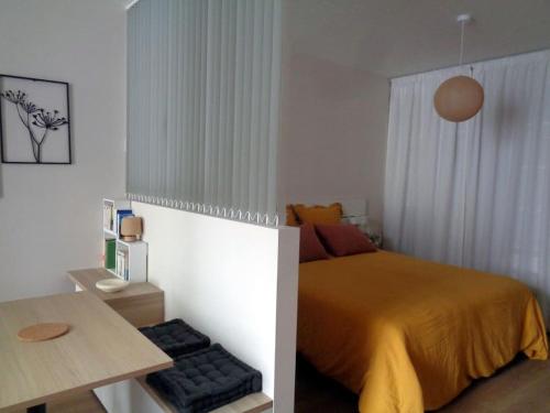 una piccola camera da letto con un letto e un tavolo di Appartement Hestia F1 bis + terrasse hyper centre a Lons-le-Saunier