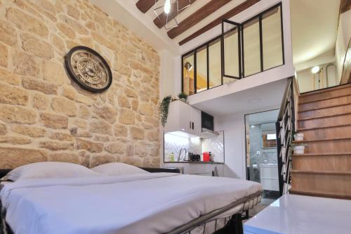 une chambre avec un grand lit et un mur en pierre dans l'établissement Modern Tasty Loft Saint Germain Latin Quarter, à Paris