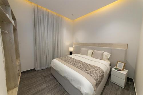 een slaapkamer met een groot wit bed en een raam bij شقة بغرفتي نوم بتصميم أنيق مع مدخل خاص in Riyad
