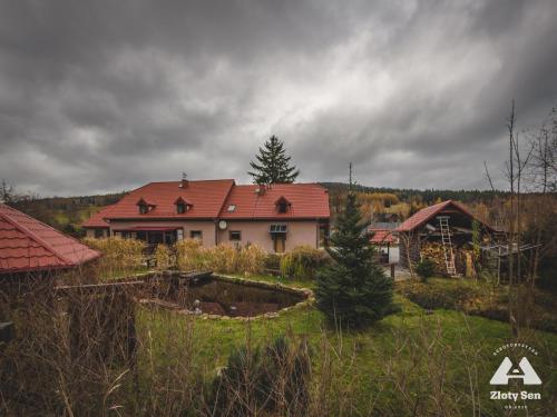 a house with a red roof in a yard at Złoty Sen Agroturystyka in Stronie Śląskie