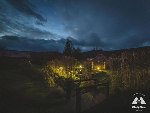 a night view of a garden with a house with lights at Złoty Sen Agroturystyka in Stronie Śląskie