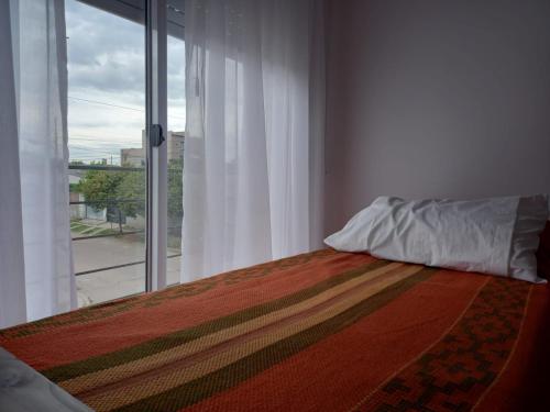 um quarto com uma cama e uma grande janela em DEPARTAMENTOS GCHU em Gualeguaychú