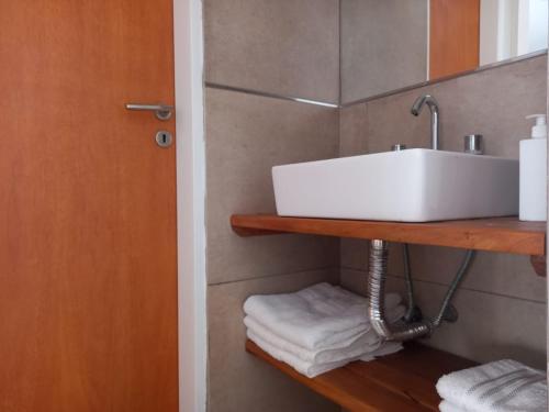 a bathroom with a sink and towels on a shelf at DEPARTAMENTOS GCHU in Gualeguaychú