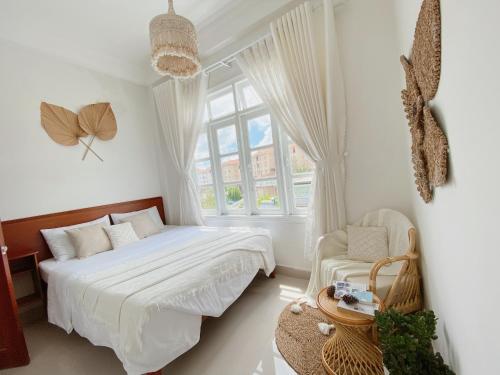 a white bedroom with a bed and a window at Lantana Homestay in Da Lat