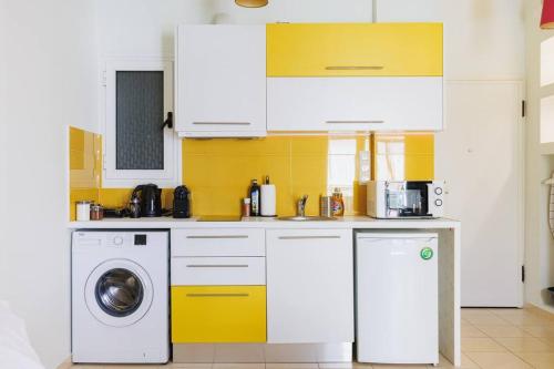 a kitchen with white cabinets and a washer and dryer at Relaxing studio in Athens city center in Athens