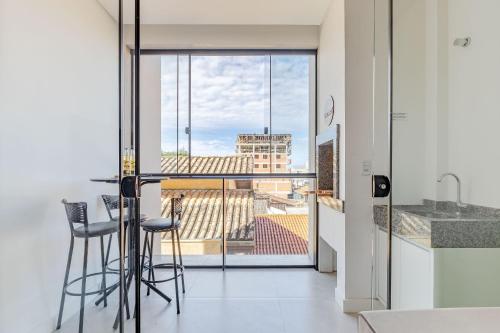 una cucina con tavolo e sedie e un balcone di Apartamento, Com Piscina - 350m da Praia de Bombas - 2 Suítes, 6 Pessoas a Bombinhas