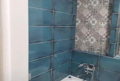 een blauw betegelde badkamer met een wastafel en een spiegel bij VIP apart 560 in Tbilisi City