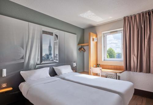 a hotel room with two beds and a window at B&B HOTEL Caen Mémorial in Caen