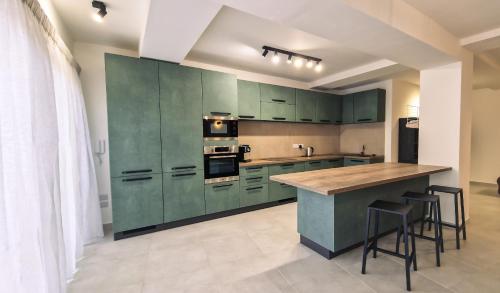a kitchen with green cabinets and a counter with stools at Mgarr ix-Xini Holiday apartment in Xewkija