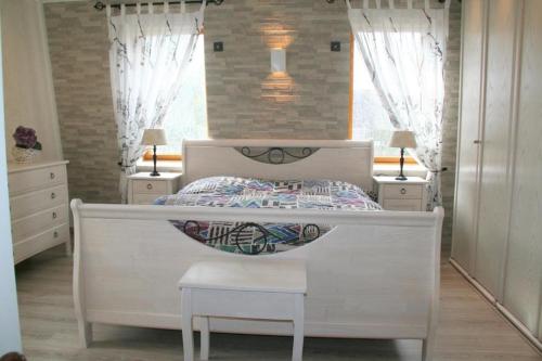 ein Schlafzimmer mit einem Bett, zwei Nachttischen und zwei Fenstern in der Unterkunft Heggerank 23B* in Nieuwvliet