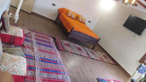 1 dormitorio con 1 cama naranja y 2 alfombras en Chez karim, en Ifrane