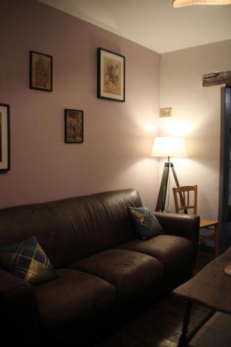 ein Wohnzimmer mit einem braunen Sofa und einer Lampe in der Unterkunft Gîte du Chat noir (Brocéliande) in Campénéac
