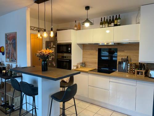 une cuisine avec des armoires blanches et un comptoir avec des tabourets dans l'établissement Appartement La Madeleine - Proximité Lille, à Lille