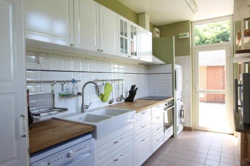 a kitchen with white cabinets and a sink at Les Pommes d'Or in Marly-Gomont