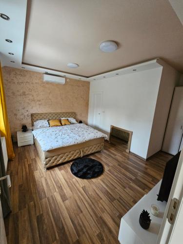 een slaapkamer met een groot bed en een houten vloer bij L&V Apartmani in Novi Grad