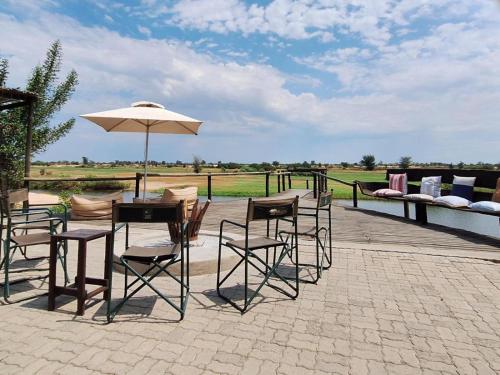 a patio with a table and chairs and an umbrella at Zambezi King Fisher Lodge in Katima Mulilo