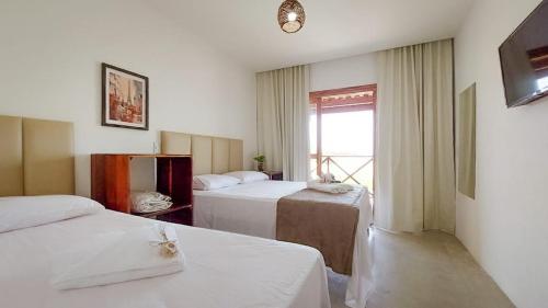 a hotel room with two beds and a window at Pousada Via do Sol - Icaraí de Amontada in Icaraí