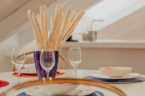 a table with two wine glasses and plates on it at Aphrodite Luxury APT with Jacuzzi in Trieste