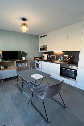 une cuisine avec une table et des chaises dans une pièce dans l'établissement Studio Hermine neuf pour 2 personnes au cœur de St, à Saint-Malo