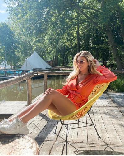 a woman sitting in a chair by the water at ASILI DELUXE - Zebra in Lichtaart