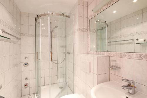 a white bathroom with a shower and a sink at Haus & Villa Strandburg by Rujana in Binz