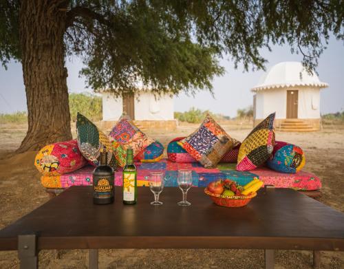 Sonal Desert Camp Jaisalmer في جيلسامر: أريكة مع زجاجات النبيذ والاكواب على طاولة