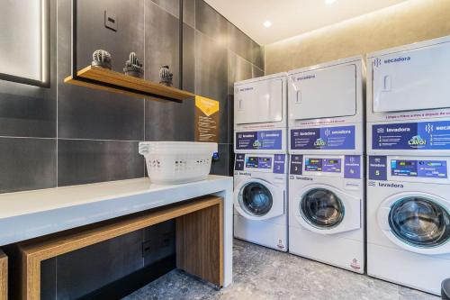 a laundry room with three washing machines and a counter at GO 24 by My Way in Porto Alegre