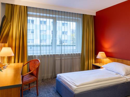 um quarto de hotel com uma cama, uma secretária e uma janela em Good Morning + Berlin City East em Berlim