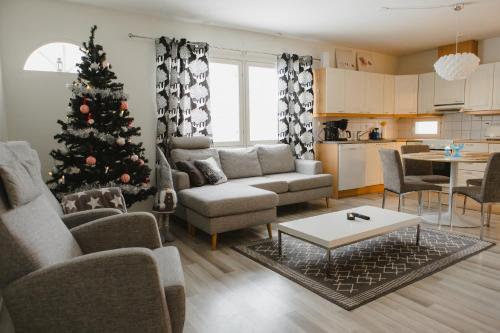 a living room with a christmas tree and a couch at Paritalohuoneisto lähellä Joulupukin Pajakylää in Rovaniemi