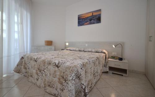 sypialnia z dużym łóżkiem i stolikiem nocnym z narzutą w obiekcie Residenza Marco Polo w Lignano Sabbiadoro