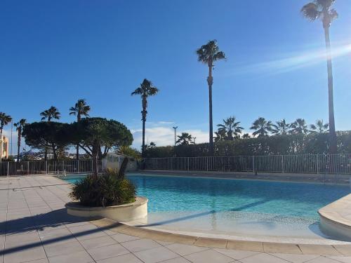 une piscine avec des palmiers en arrière-plan dans l'établissement CAP HERMES Vue MER 3 Pieces 70m2 Climatise 4 Perso, à Fréjus