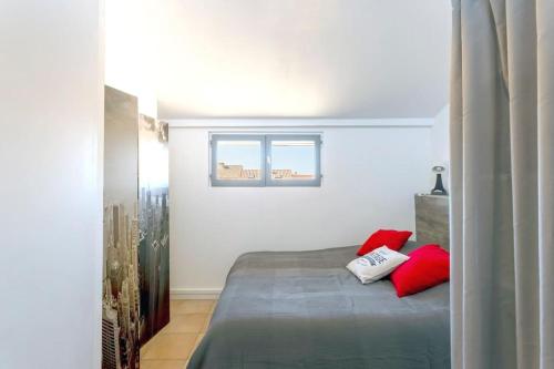- une chambre avec un lit doté d'oreillers rouges dans l'établissement Chez Audrey - Agréable appartement duplex climatisé et convivial, au Grau-du-Roi