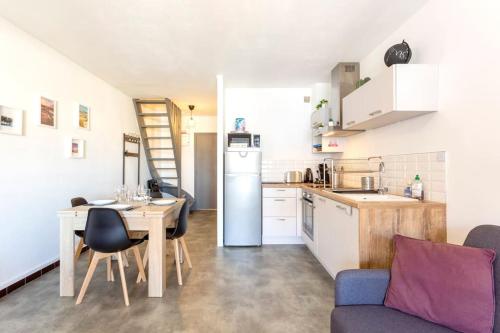 une cuisine et une salle à manger avec une table et un réfrigérateur dans l'établissement Chez Audrey - Agréable appartement duplex climatisé et convivial, au Grau-du-Roi