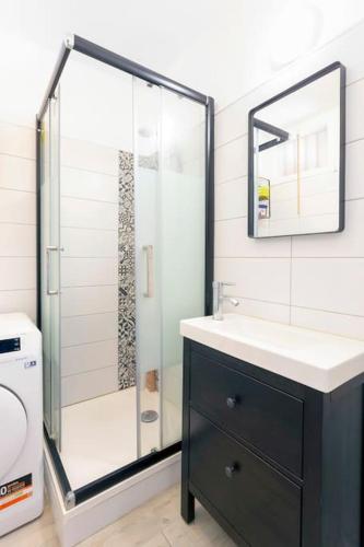 une salle de bain avec une douche en verre et un lavabo dans l'établissement Chez Audrey - Agréable appartement duplex climatisé et convivial, au Grau-du-Roi