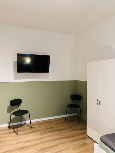 two chairs in a room with a tv on a wall at Monteurswohnung an der Mulde in Döbeln